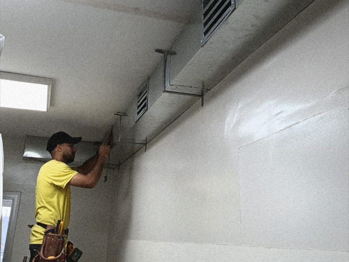 Técnico instalando conductos de aire acondicionado con rejillas de ventilación